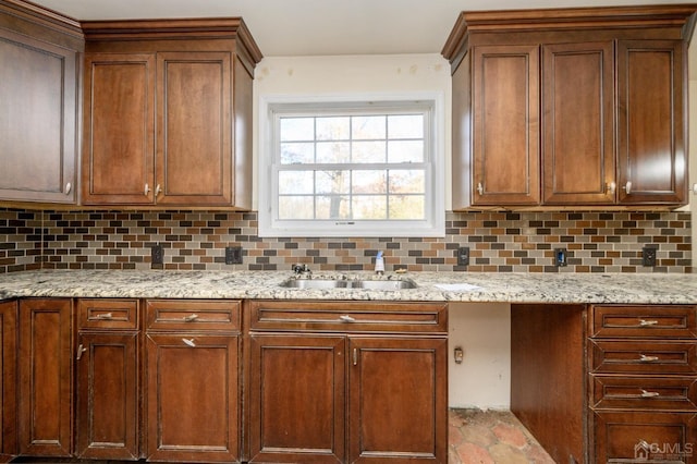 kitchen featuring light stone counters, a sink, and tasteful backsplash
