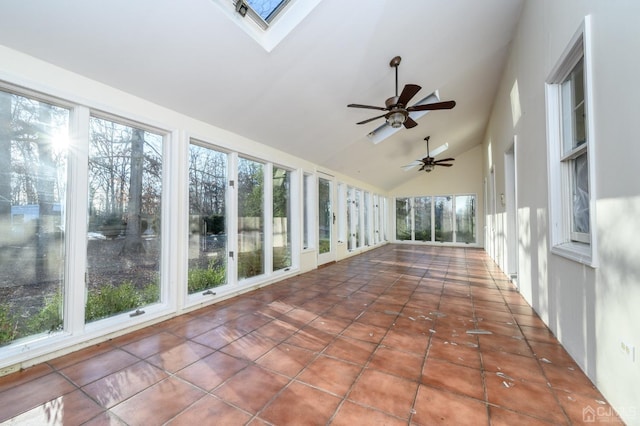 unfurnished sunroom with a skylight, tile patterned flooring, and high vaulted ceiling