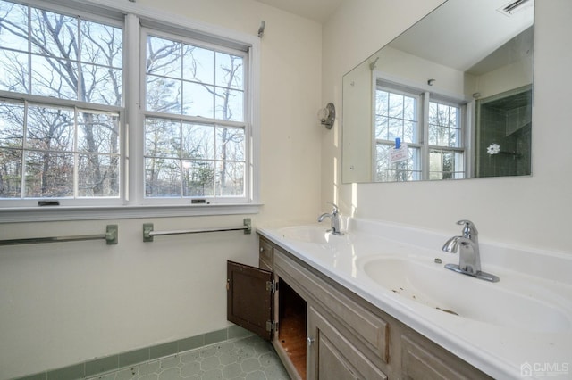 bathroom featuring a sink, baseboards, double vanity, and visible vents