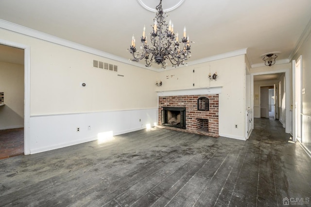 unfurnished living room with visible vents, a brick fireplace, an inviting chandelier, ornamental molding, and dark wood-type flooring