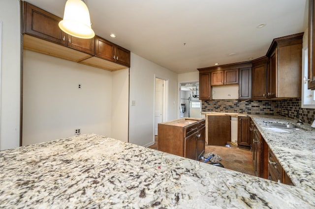 kitchen featuring light stone counters, a sink, backsplash, and recessed lighting