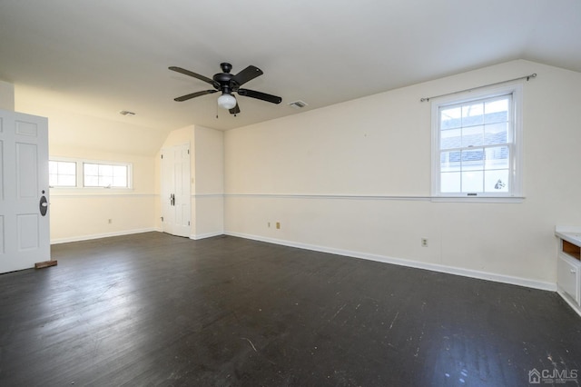 interior space featuring dark wood-style flooring, ceiling fan, vaulted ceiling, and visible vents