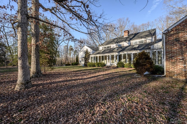 back of house featuring brick siding and a chimney