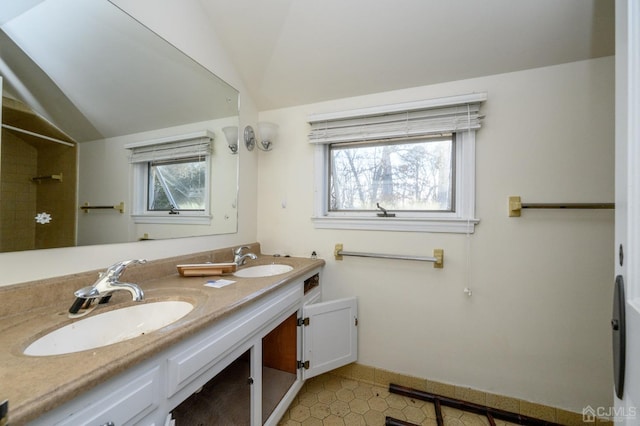 bathroom with a sink, vaulted ceiling, and a healthy amount of sunlight