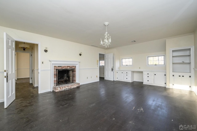 unfurnished living room featuring built in features, a fireplace, built in desk, baseboards, and a chandelier