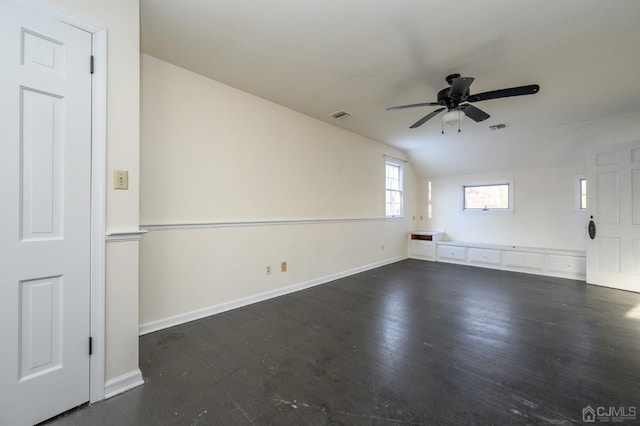empty room featuring visible vents, a ceiling fan, baseboards, and vaulted ceiling