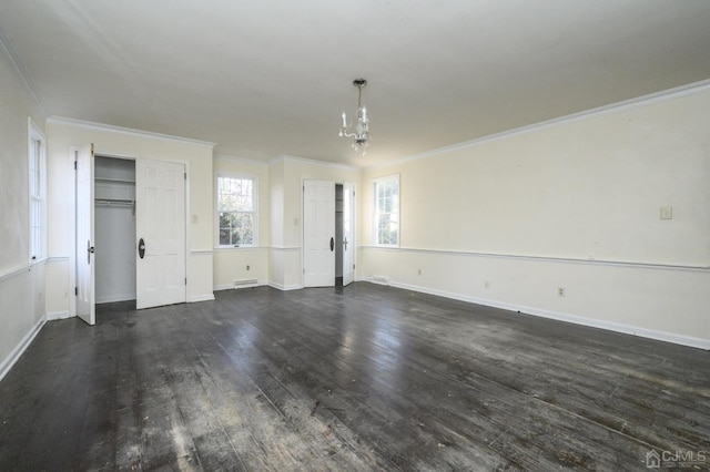 unfurnished living room featuring dark wood-type flooring, ornamental molding, and a chandelier