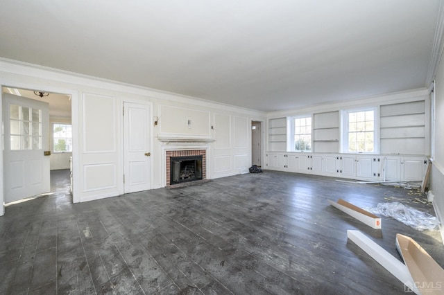 unfurnished living room featuring crown molding, a brick fireplace, and dark wood-type flooring