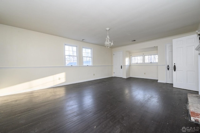 empty room with dark wood-type flooring, baseboards, a notable chandelier, and visible vents