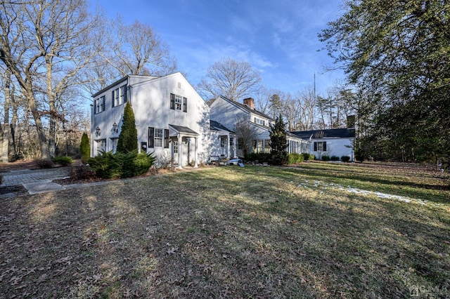 view of side of property with a chimney and a yard