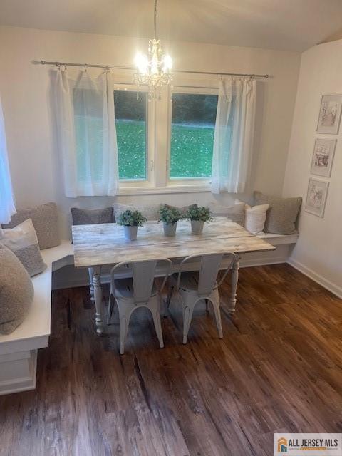 dining space featuring breakfast area, baseboards, a notable chandelier, and wood finished floors