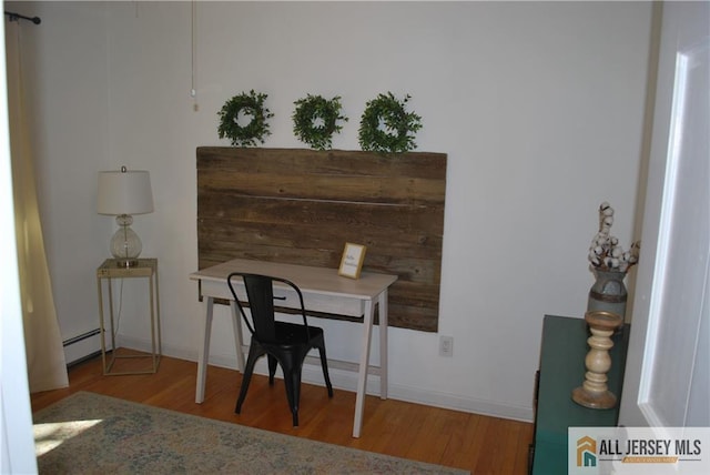 office featuring wood finished floors, baseboards, and a baseboard radiator