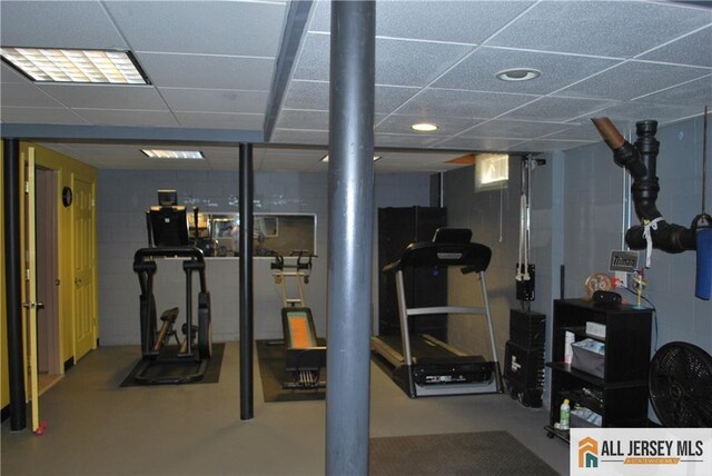 exercise room featuring concrete block wall and a paneled ceiling