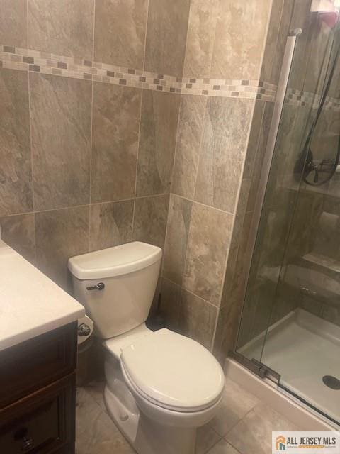 full bath with vanity, toilet, a stall shower, and tile patterned flooring