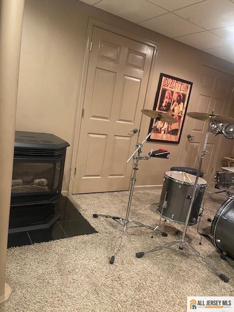 playroom with a paneled ceiling and a wood stove