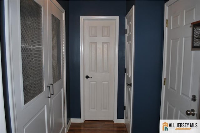 corridor with dark wood-style floors and baseboards