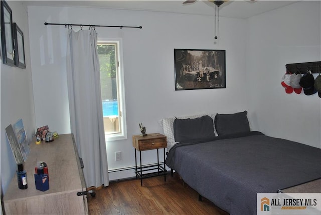 bedroom featuring baseboard heating and wood finished floors