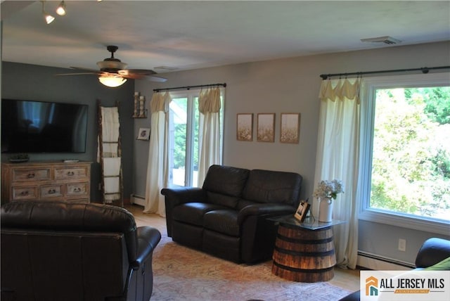 living area featuring a baseboard heating unit, visible vents, and ceiling fan