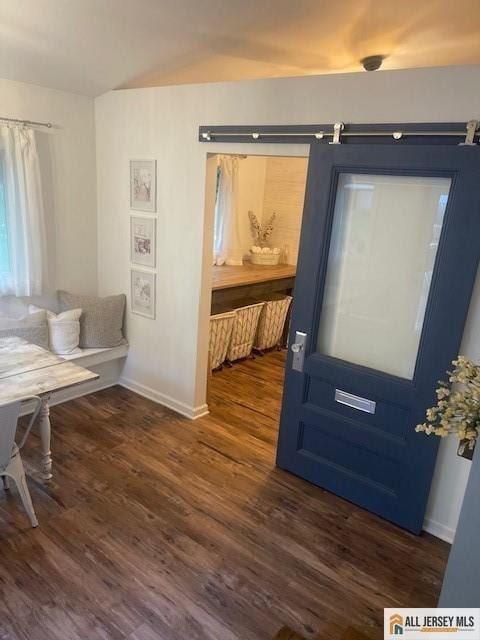 foyer featuring a barn door, baseboards, and dark wood-style flooring