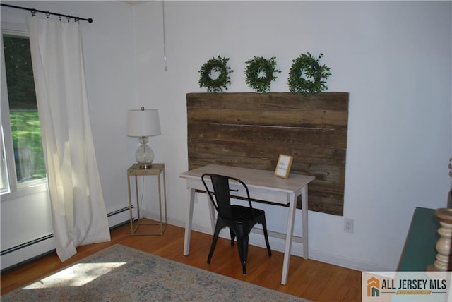 office featuring a baseboard heating unit, baseboards, and wood finished floors