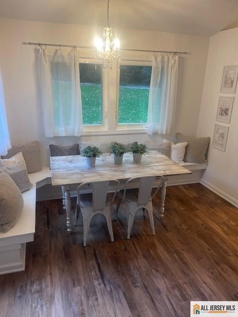 dining area with a chandelier, breakfast area, baseboards, and wood finished floors