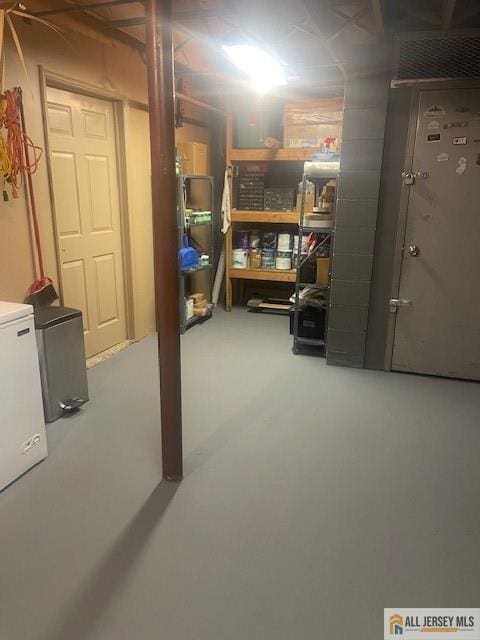 unfinished basement with fridge