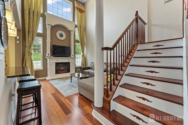 2420 Canterbury Ln, North Brunswick, NJ 08902 - entrance foyer featuring wood finished floors, a glass covered fireplace, ornate columns, a high ceiling, and stairs