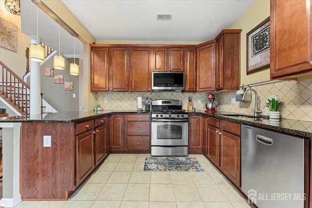 2420 Canterbury Ln, North Brunswick, NJ 08902 - kitchen with stainless steel appliances, a sink, a peninsula, dark stone countertops, and backsplash