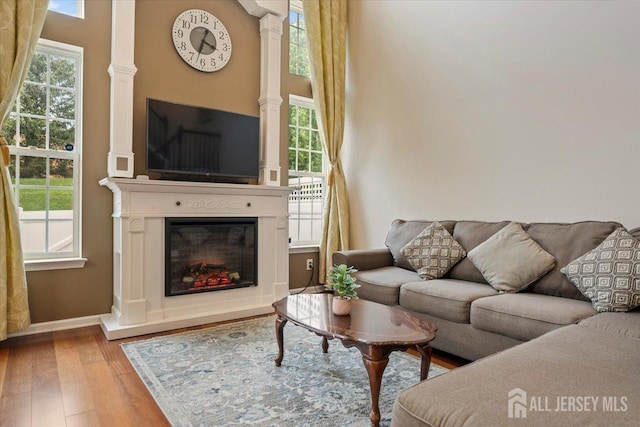 2420 Canterbury Ln, North Brunswick, NJ 08902 - living room featuring wood finished floors, baseboards, a glass covered fireplace, and a towering ceiling