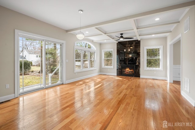 unfurnished living room featuring baseboards, light wood finished floors, visible vents, coffered ceiling, and beamed ceiling