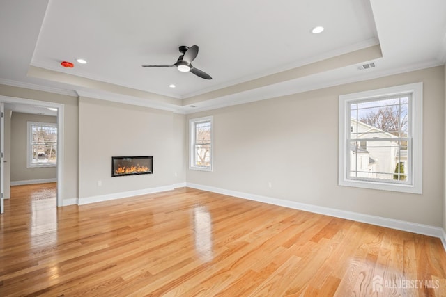 unfurnished living room with a raised ceiling, plenty of natural light, and visible vents