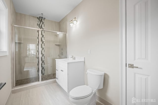 bathroom with vanity, a shower stall, toilet, and baseboards