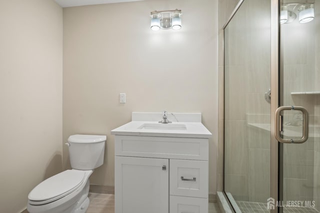 bathroom featuring vanity, a shower stall, and toilet