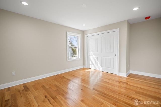 unfurnished bedroom featuring a closet, recessed lighting, light wood-style flooring, and baseboards