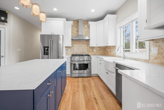 kitchen featuring white cabinets, wall chimney range hood, high quality appliances, and blue cabinets