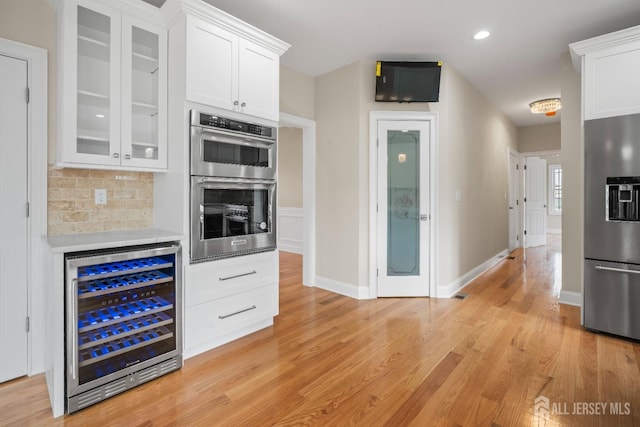 kitchen with glass insert cabinets, wine cooler, white cabinets, and appliances with stainless steel finishes