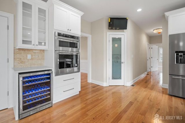 kitchen featuring white cabinetry, stainless steel appliances, wine cooler, and glass insert cabinets
