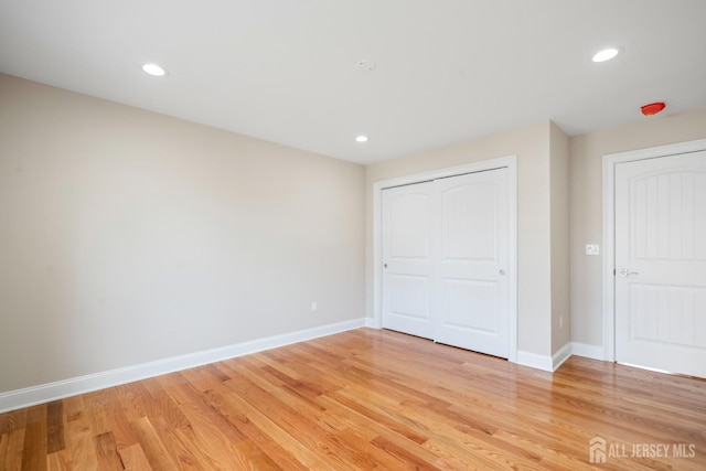 unfurnished bedroom with light wood finished floors, baseboards, recessed lighting, and a closet