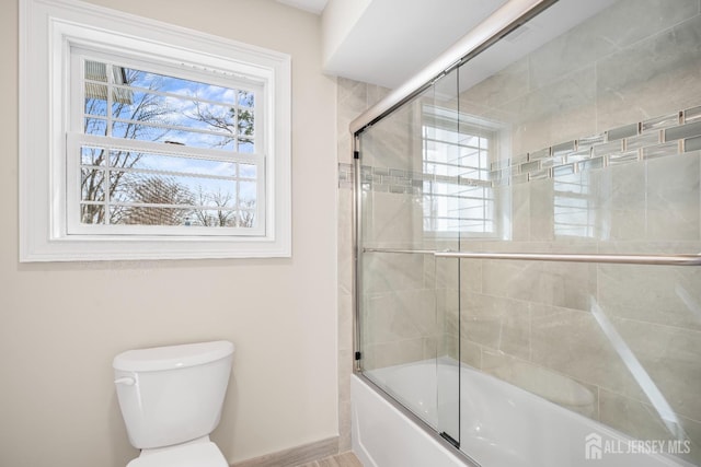 bathroom featuring enclosed tub / shower combo and toilet