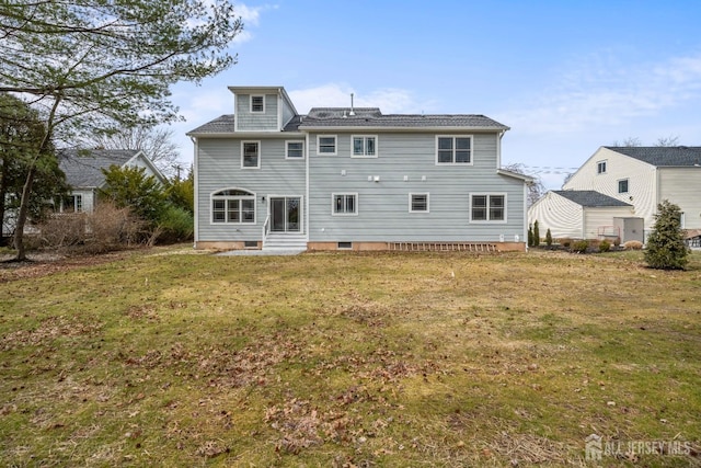 back of property featuring entry steps and a yard