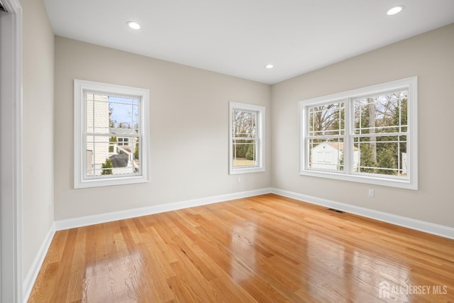 unfurnished room with light wood finished floors, visible vents, recessed lighting, and baseboards