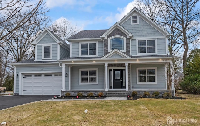 craftsman inspired home with a front lawn, driveway, a porch, stone siding, and a garage