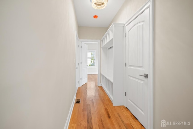 corridor featuring baseboards, visible vents, and light wood-type flooring