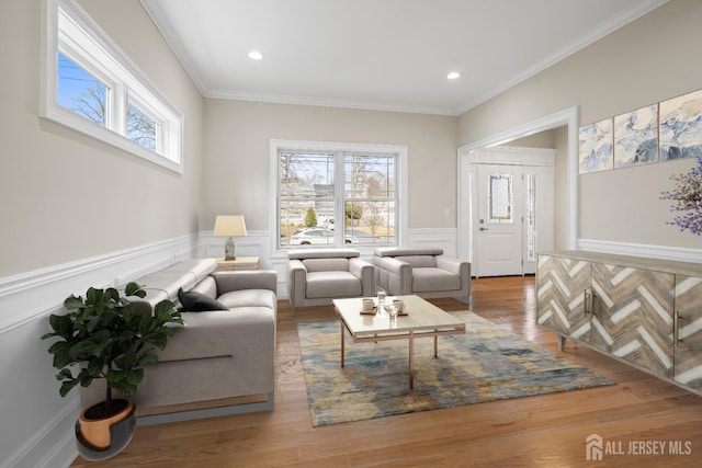 living room featuring wainscoting, crown molding, wood finished floors, and plenty of natural light