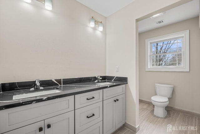 full bath featuring toilet, baseboards, visible vents, and a sink