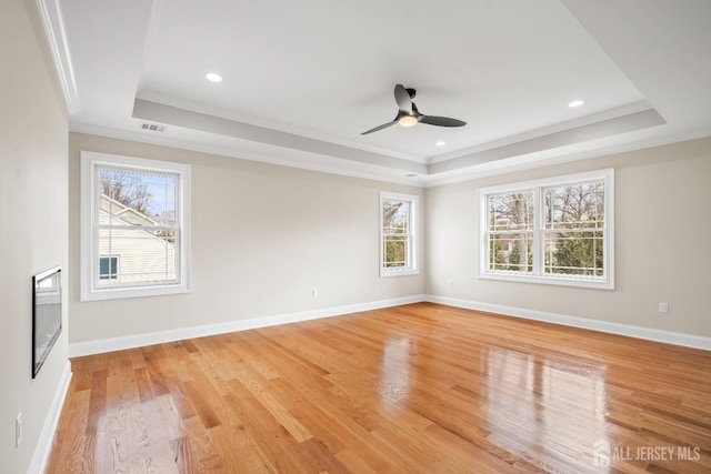 spare room featuring a ceiling fan, ornamental molding, light wood-style floors, and a raised ceiling