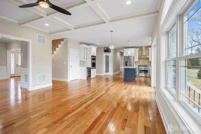 unfurnished living room with coffered ceiling, beam ceiling, visible vents, and light wood-type flooring