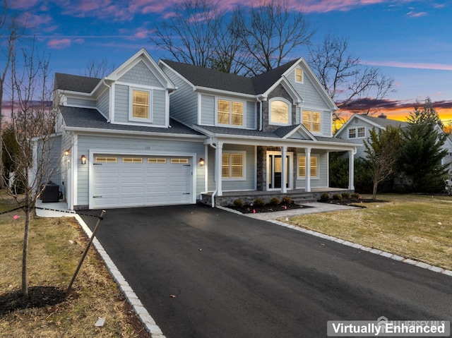 traditional-style house with a yard, cooling unit, driveway, covered porch, and a garage
