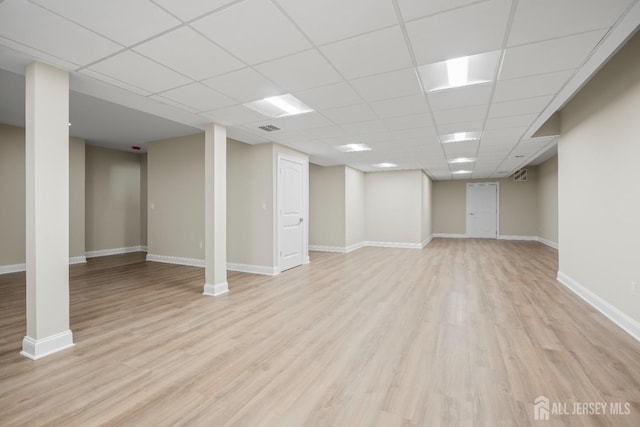 finished below grade area with a paneled ceiling, baseboards, and light wood-style flooring