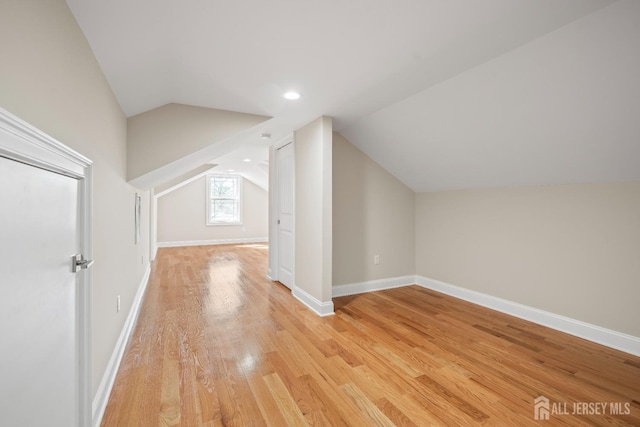 bonus room with lofted ceiling, baseboards, and light wood-type flooring